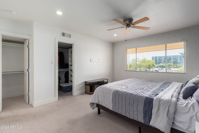 carpeted bedroom with ceiling fan, a closet, and a walk in closet