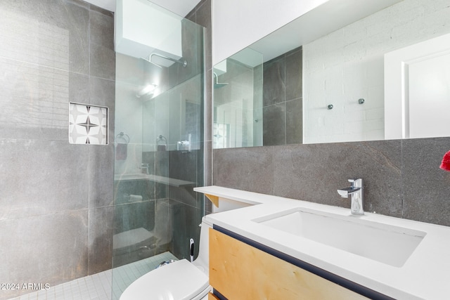 bathroom with vanity, toilet, decorative backsplash, and a tile shower