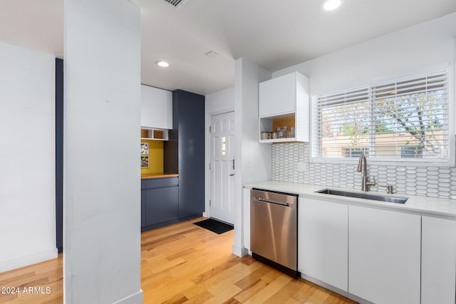 kitchen with white cabinetry, stainless steel dishwasher, sink, and light hardwood / wood-style floors