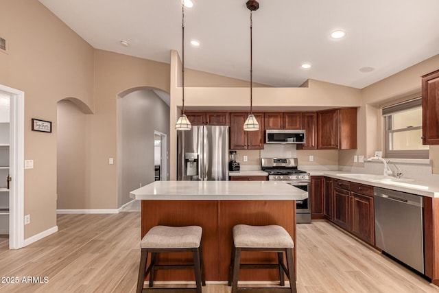 kitchen with vaulted ceiling, stainless steel appliances, a sink, and light countertops