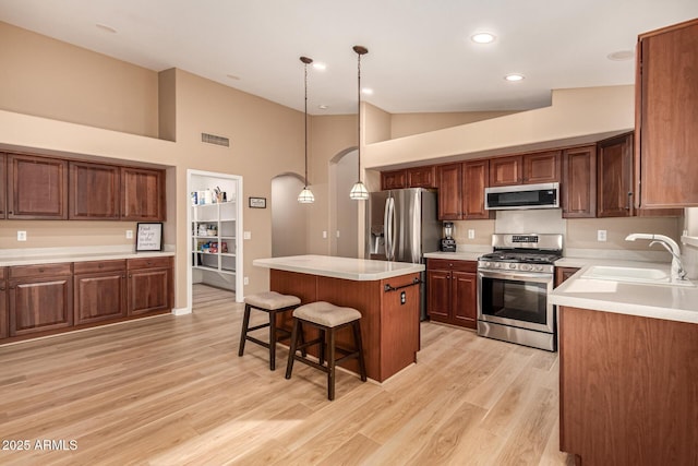 kitchen with a center island, visible vents, appliances with stainless steel finishes, a sink, and a kitchen breakfast bar