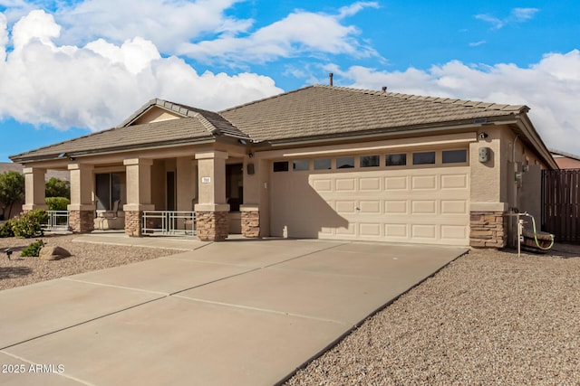 view of front facade featuring a garage, concrete driveway, stone siding, covered porch, and stucco siding