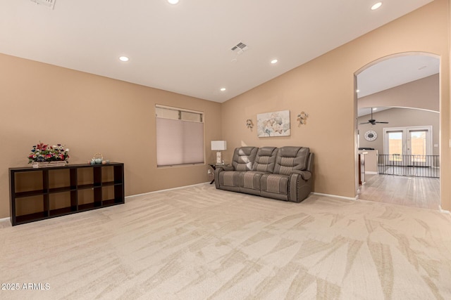 carpeted living area with visible vents, arched walkways, baseboards, lofted ceiling, and recessed lighting