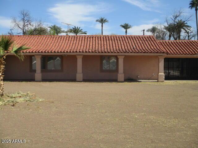 rear view of property with a tile roof and stucco siding