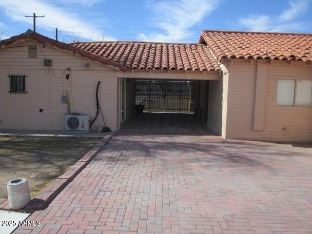 exterior space with a tiled roof, decorative driveway, and ac unit