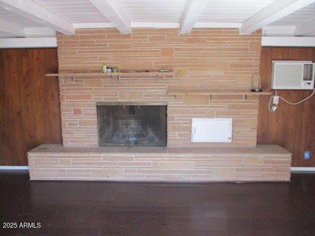 room details with beam ceiling, a large fireplace, wood walls, wood finished floors, and a wall mounted air conditioner