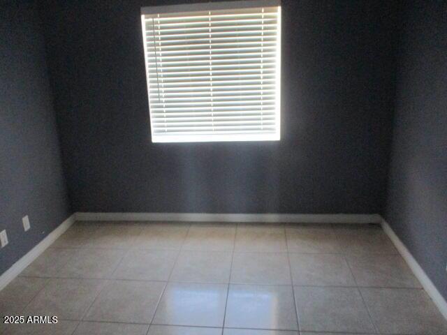 empty room with light tile patterned flooring and baseboards