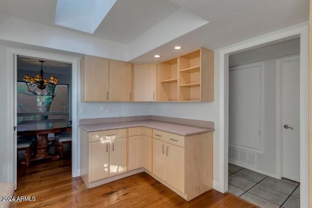 kitchen featuring a skylight, light brown cabinets, a chandelier, and light hardwood / wood-style flooring