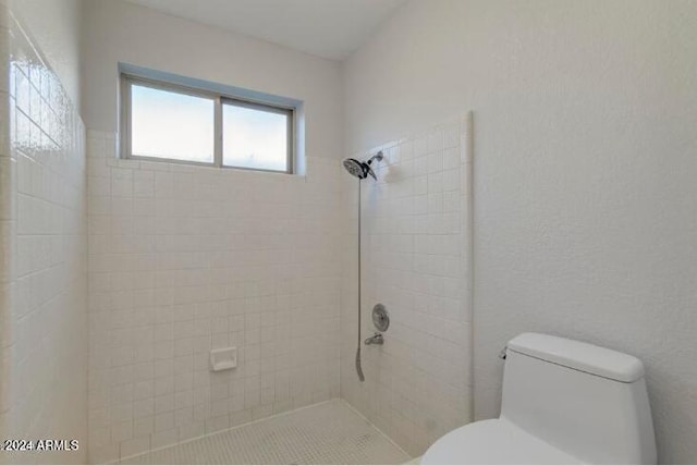 bathroom featuring a tile shower and toilet