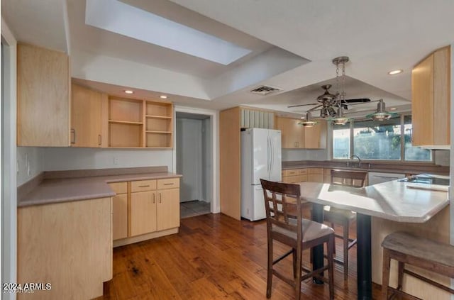 kitchen with kitchen peninsula, a raised ceiling, ceiling fan, light brown cabinets, and white refrigerator