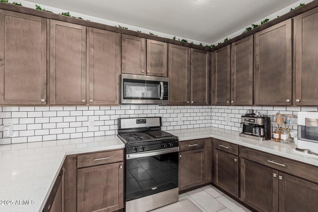 2640 N Heritage St, Buckeye, AZ 85396 - kitchen with decorative backsplash, dark brown cabinets, light tile patterned floors, and appliances with stainless steel finishes