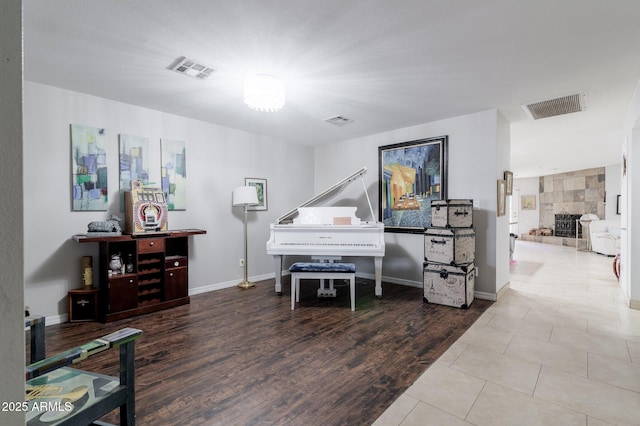 living area featuring baseboards, a fireplace, visible vents, and wood finished floors