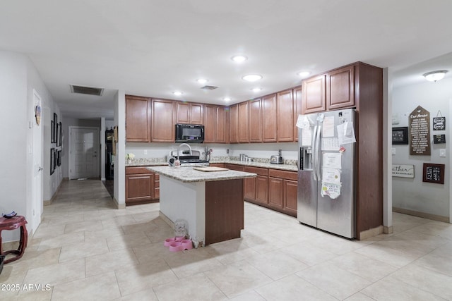 kitchen featuring recessed lighting, visible vents, appliances with stainless steel finishes, light stone countertops, and an island with sink