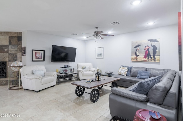 living area with ceiling fan, a tile fireplace, visible vents, and recessed lighting