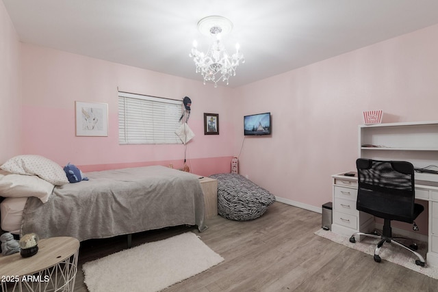 bedroom with baseboards, light wood-style flooring, and a notable chandelier