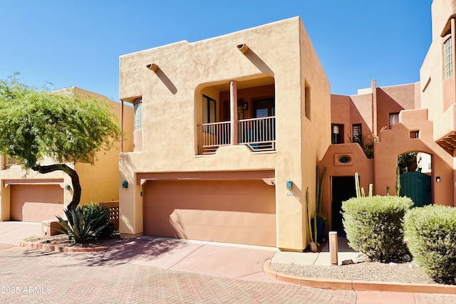 pueblo-style house featuring a balcony and a garage