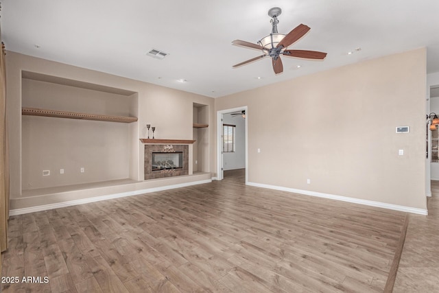 unfurnished living room featuring light hardwood / wood-style floors, built in features, a high end fireplace, and ceiling fan