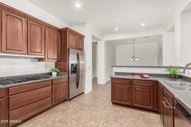 kitchen featuring decorative light fixtures, range hood, sink, appliances with stainless steel finishes, and a chandelier