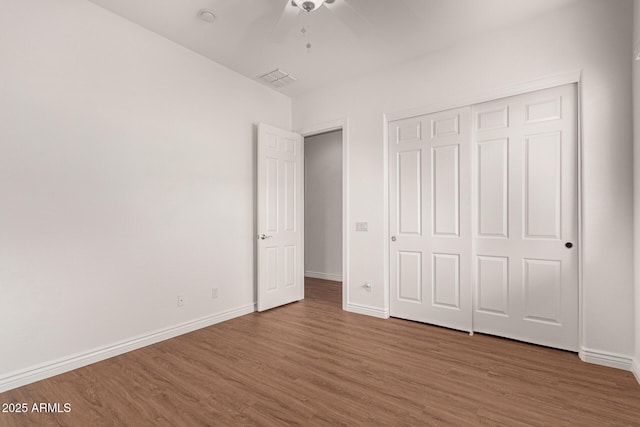 unfurnished bedroom featuring ceiling fan, a closet, and hardwood / wood-style flooring