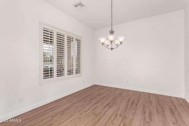 spare room featuring hardwood / wood-style flooring and a notable chandelier