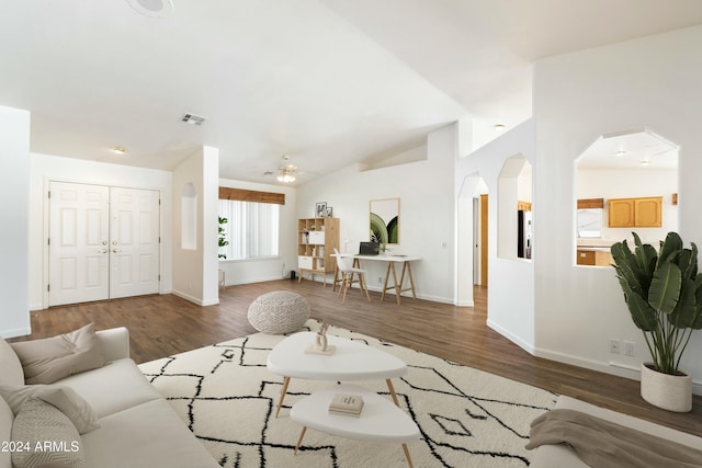 living area featuring arched walkways, visible vents, ceiling fan, and wood finished floors