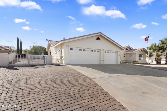 ranch-style home featuring stucco siding, concrete driveway, a gate, fence, and a garage