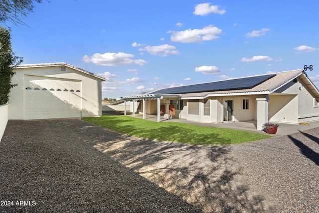 view of front facade featuring a detached garage, a tiled roof, a patio area, roof mounted solar panels, and stucco siding