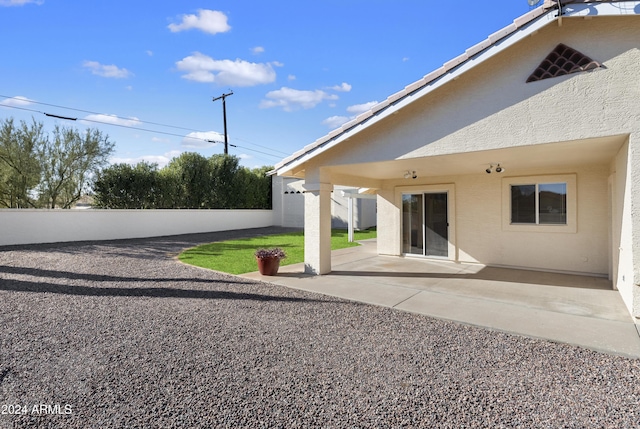 rear view of house with stucco siding, a fenced backyard, and a patio