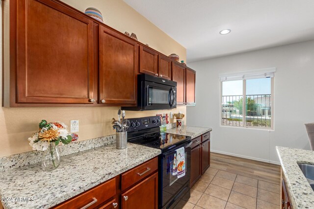 17540 W Glenhaven Dr, Goodyear, AZ 85338 - kitchen featuring light stone countertops, light tile patterned flooring, baseboards, and black appliances