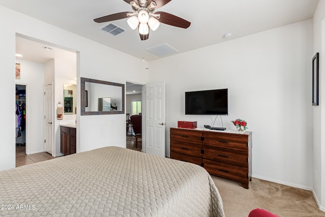 bedroom with light colored carpet, ensuite bath, a closet, and ceiling fan