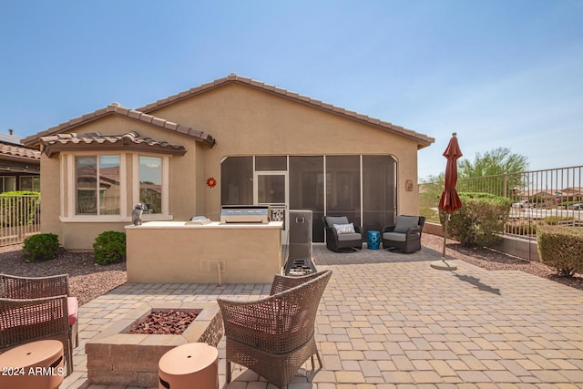 17540 W Glenhaven Dr, Goodyear, AZ 85338 - view of patio featuring exterior kitchen, a sunroom, fence, and an outdoor living space with a fire pit