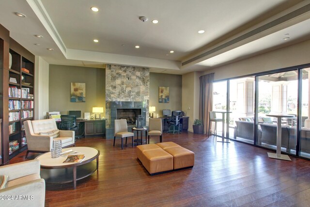 living room featuring a tray ceiling, hardwood / wood-style flooring, and a fireplace