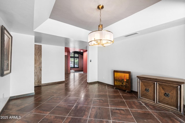 unfurnished dining area featuring a chandelier, tile patterned floors, arched walkways, and baseboards