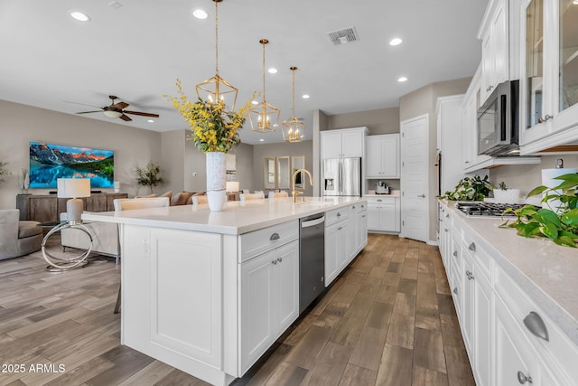 kitchen featuring visible vents, a sink, ceiling fan with notable chandelier, open floor plan, and stainless steel appliances