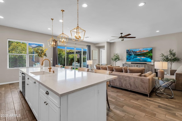 kitchen featuring a sink, light wood-style floors, ceiling fan with notable chandelier, and recessed lighting