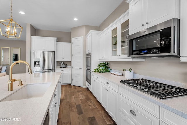 kitchen with white cabinets, appliances with stainless steel finishes, glass insert cabinets, and a sink