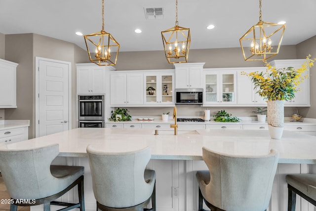 kitchen featuring visible vents, a sink, appliances with stainless steel finishes, and a chandelier