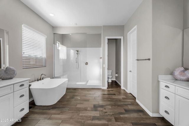 bathroom featuring toilet, tiled shower, baseboards, wood finished floors, and a soaking tub
