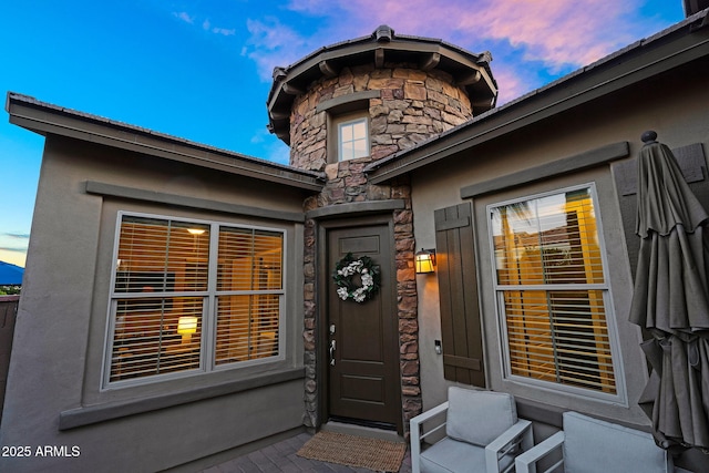 view of exterior entry featuring stucco siding and stone siding