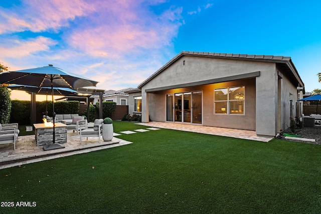 rear view of house with fence, stucco siding, an outdoor living space, a lawn, and a patio