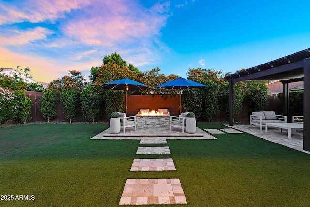yard at dusk featuring a fenced backyard, an outdoor living space with a fire pit, a patio, and a pergola
