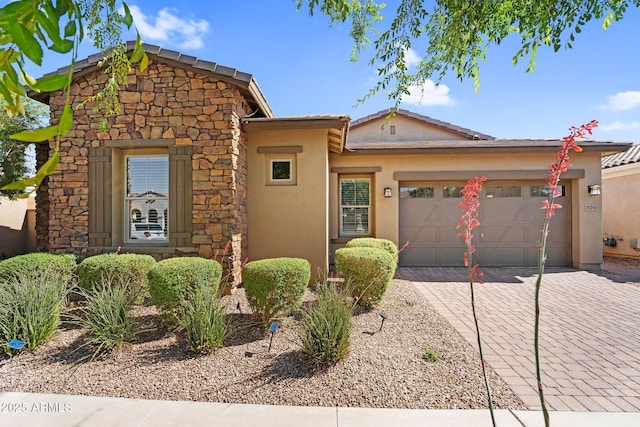 view of front of property featuring an attached garage, decorative driveway, stucco siding, and stone siding