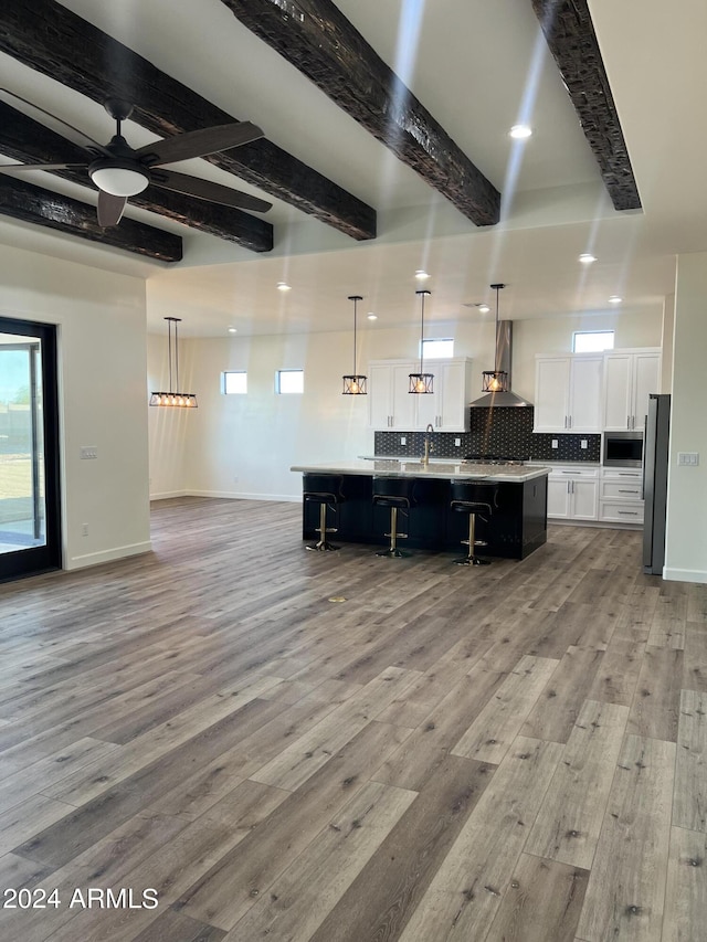 kitchen featuring a spacious island, hanging light fixtures, light wood-type flooring, appliances with stainless steel finishes, and white cabinetry