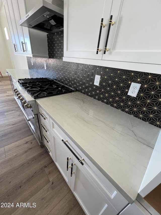 kitchen featuring light stone countertops, hardwood / wood-style flooring, white cabinetry, and exhaust hood