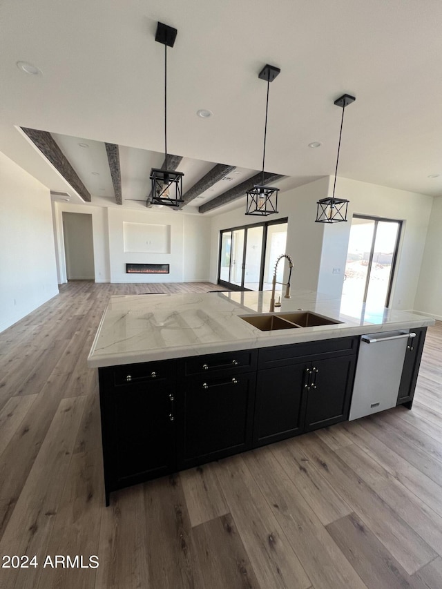 kitchen with a healthy amount of sunlight, sink, hanging light fixtures, and an island with sink