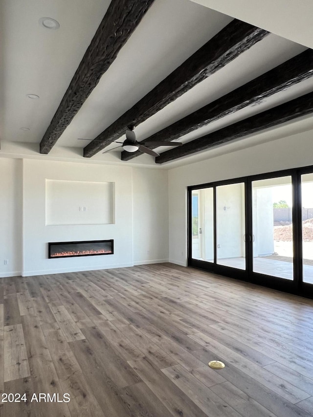 unfurnished living room with beam ceiling, hardwood / wood-style flooring, and ceiling fan