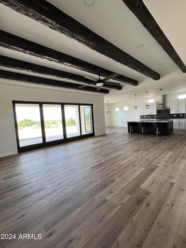 unfurnished living room with hardwood / wood-style floors, beam ceiling, and a wealth of natural light