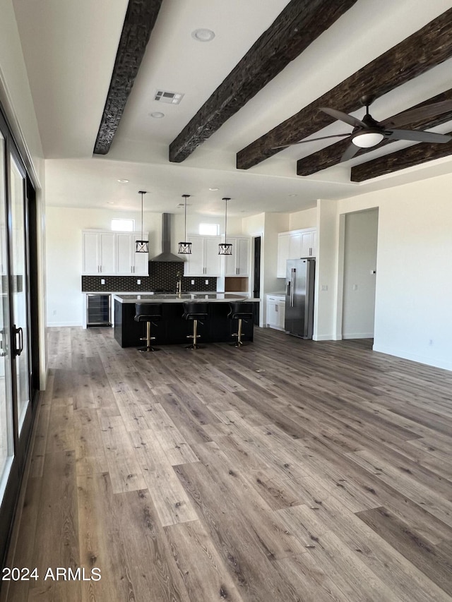 kitchen featuring a large island, pendant lighting, high quality fridge, a breakfast bar, and white cabinets