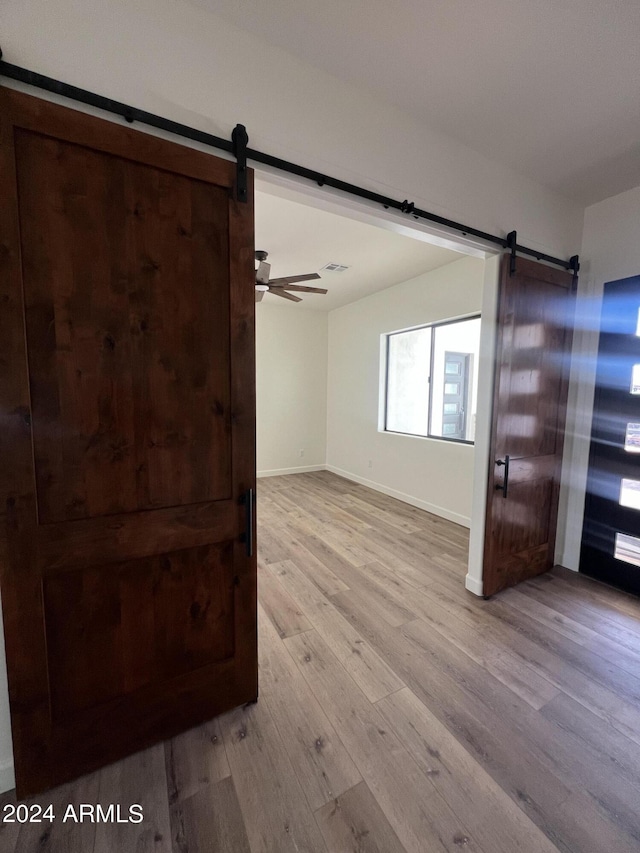 spare room featuring a barn door, light hardwood / wood-style flooring, and ceiling fan