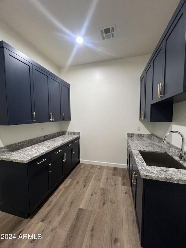 kitchen with light stone counters, light hardwood / wood-style flooring, and sink